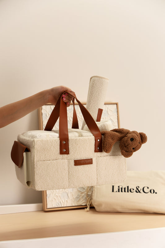 Boucle beige Caddy with brown straps and a teddy cuddly, held by a hand, on a light background with 'Little & Co.' branding.