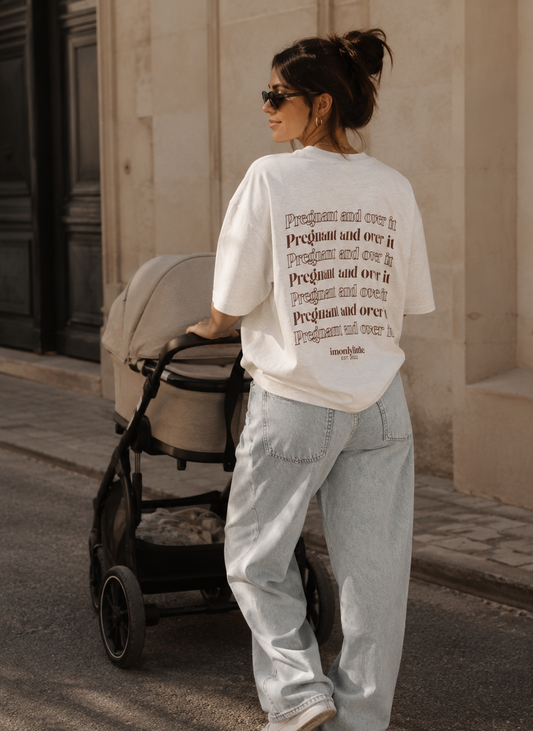Woman pushing a stroller with a text-patterned shirt in an urban setting