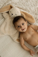 Baby lying on a soft surface with a plush toy