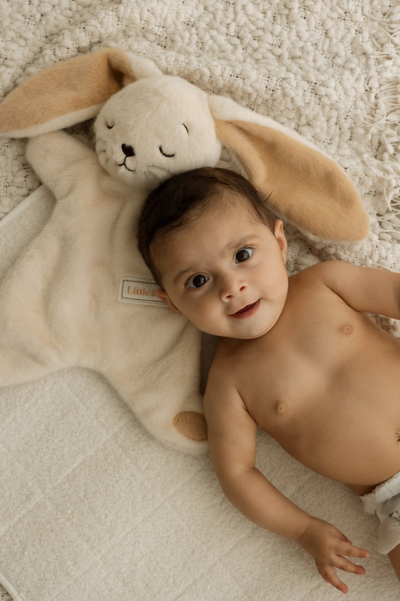 Baby lying on a soft surface with a plush toy