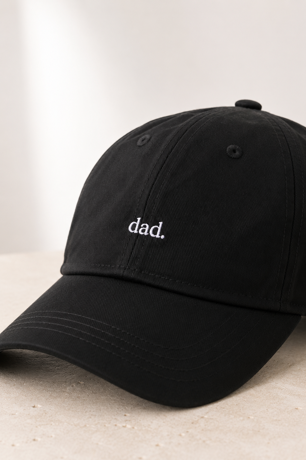 Black cap with 'dad.' embroidery on a light background