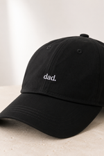Black cap with 'dad.' embroidery on a light background