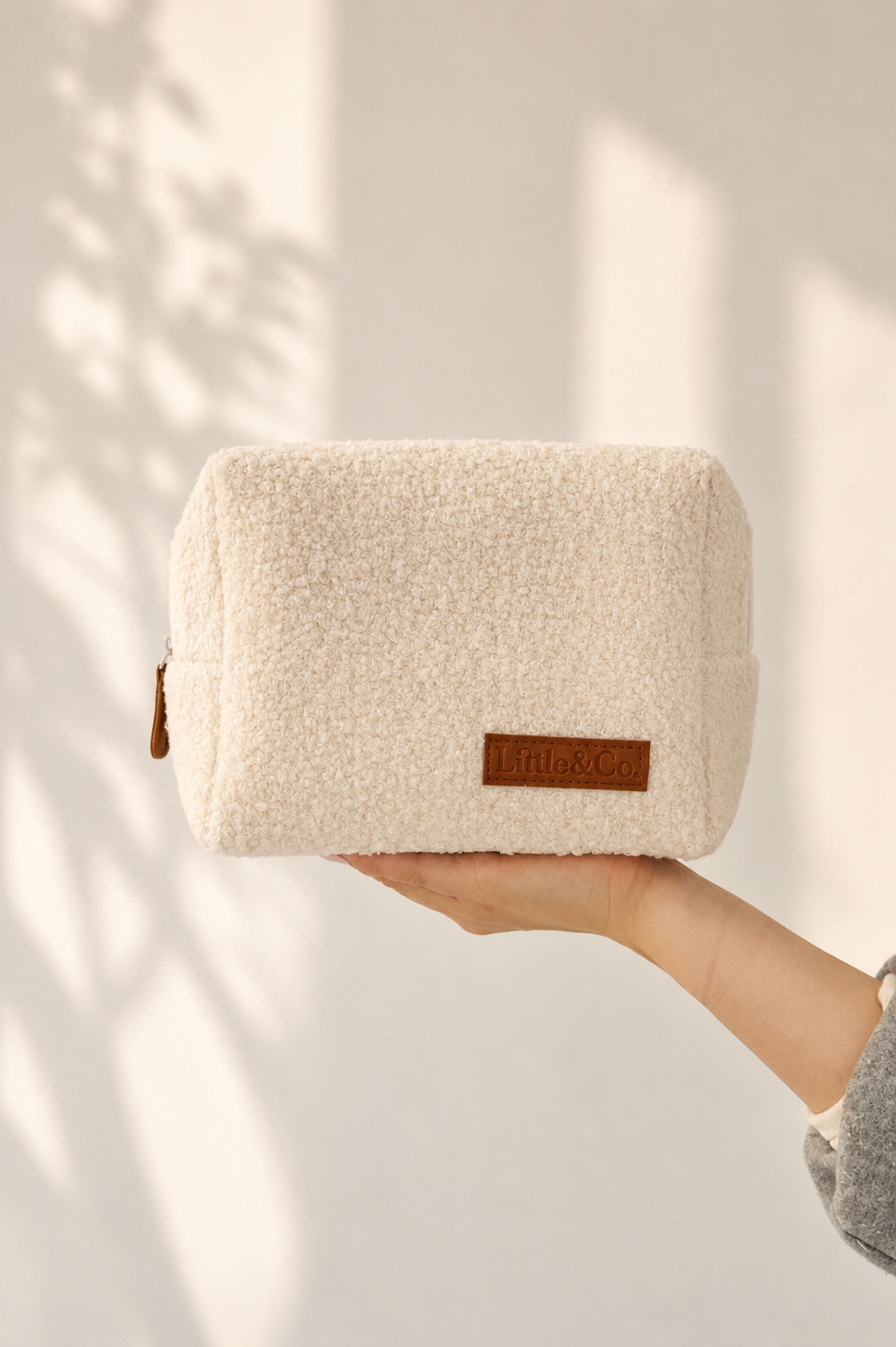 Boucle textured pouch held by a hand with a neutral background