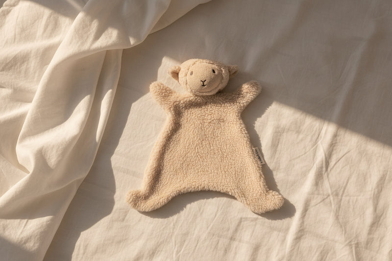 Lamb teddy cuddly on a textured beige surface
