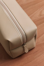 Close-up of a beige leather essentials pouch with zipper detail by Little & Co on a wooden surfac