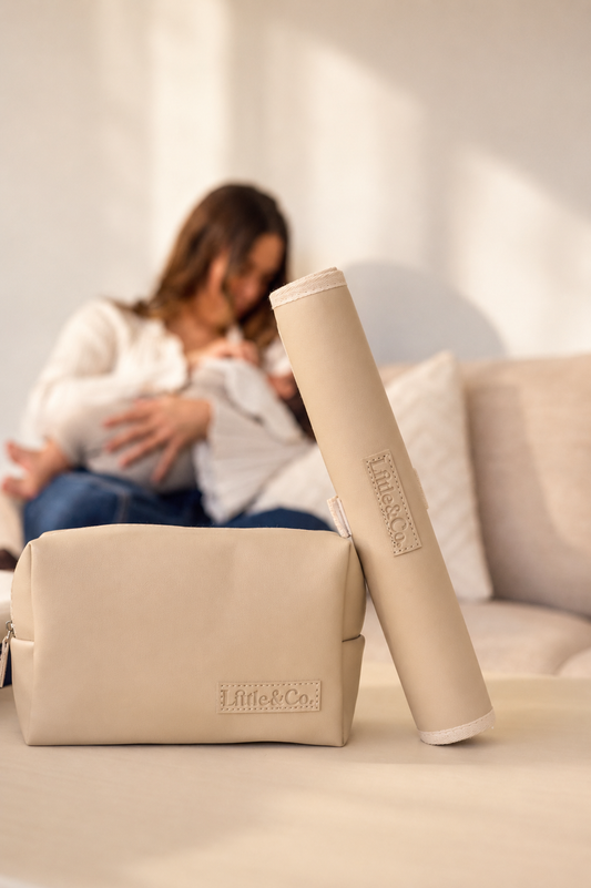 Beige pouch and cylindrical container with 'Little & Co.' branding on a blurred background of a person holding a baby.