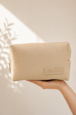 Beige pouch held by a hand Little & Co.' branding on a neutral background