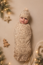 Baby wrapped in a patterned swaddle with Christmas decorations around