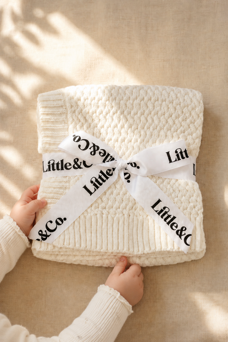 White textured blanket with a ribbon and 'Little & Co.' branding on a beige background