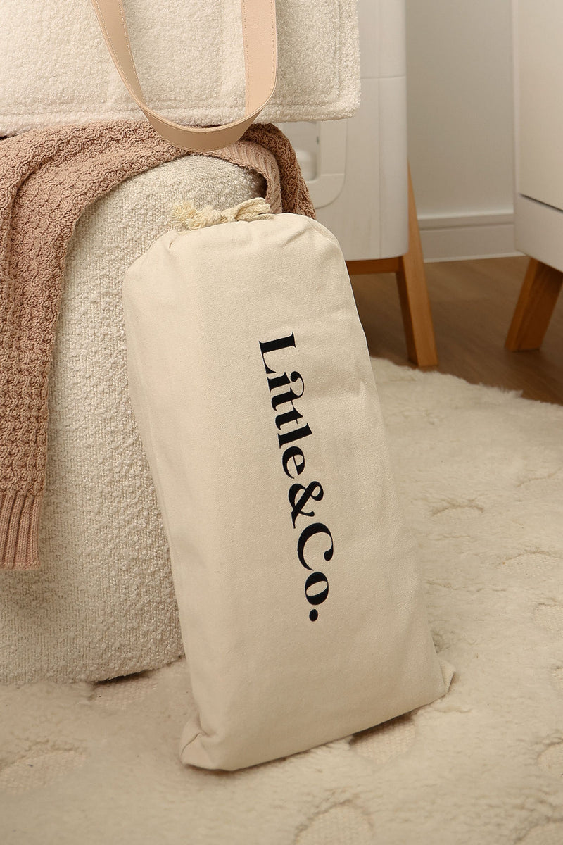 Little & Co bouclé nappy caddy stored in beige canvas dust bag with logo in neutral nursery setting