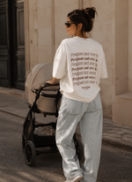 Woman pushing a stroller with a text-patterned shirt in an urban setting